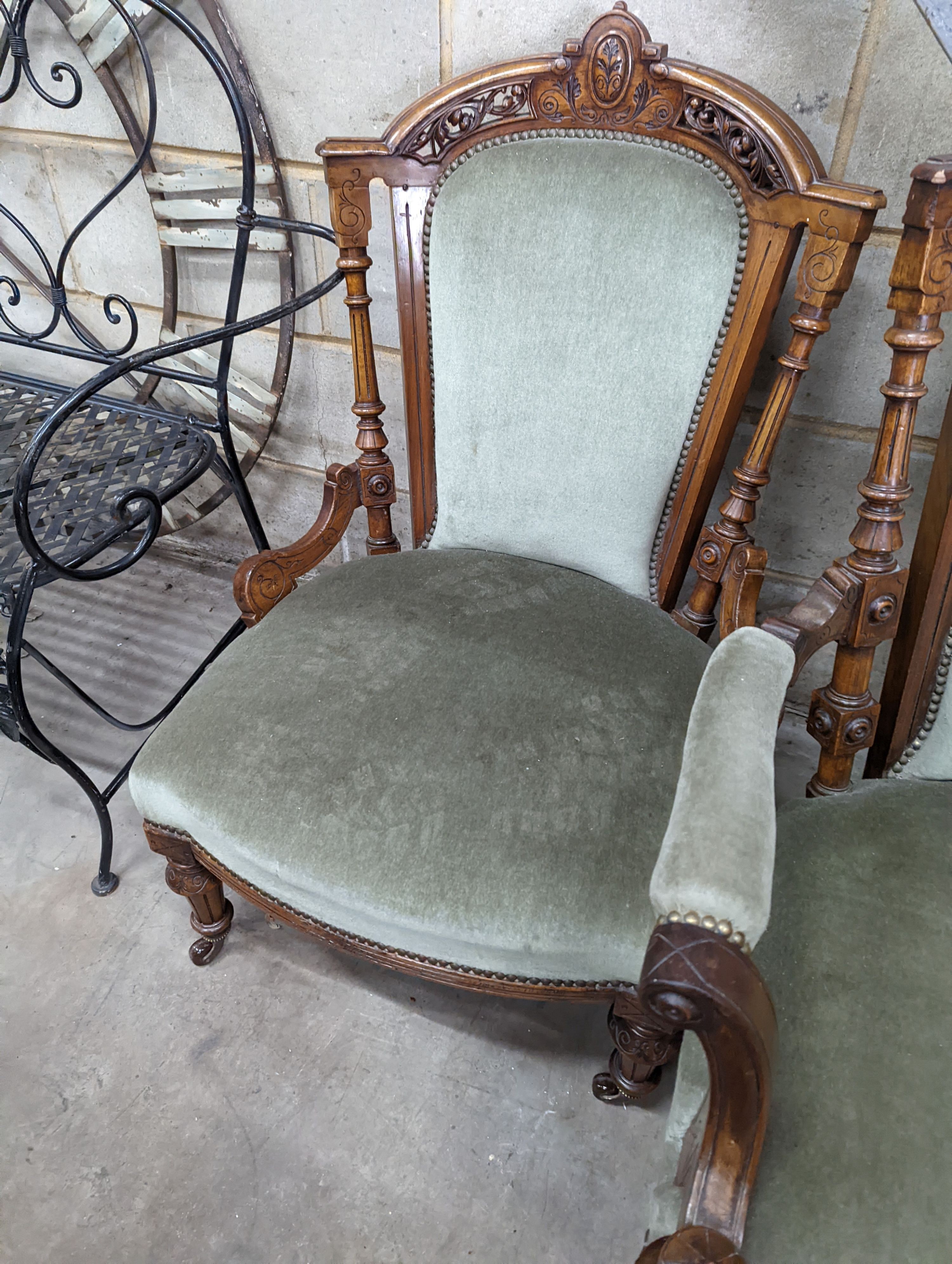 A pair of late Victorian carved walnut salon chairs upholstered in green dralon, one with arms